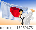 Karate practitioner kicking high in front of waving japanese flag, representing japanese martial arts and national pride 132698731