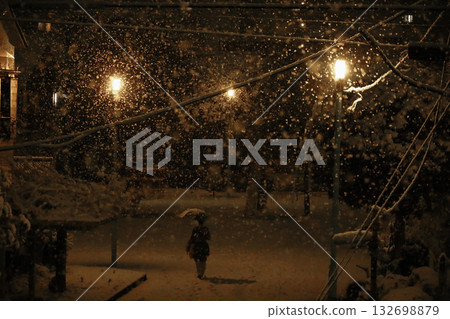 日本的日常生活：一位女子在雪夜漫步於一座小型城市公園。 132698879