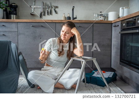 Frustrated young woman trying to assemble a chair with tools on the floor. Concept of difficulty and struggle in do it yourself project. Frustrated young woman trying to assemble a chair with tools on the floor. Concept of difficulty and struggle in do it yourself project. 132700721