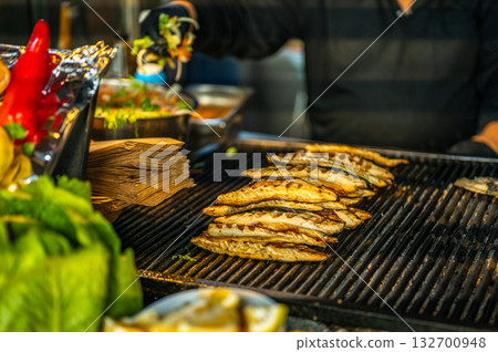 Street food chef grilling fish and adding fresh salad to Balik Ekmek sandwich, traditional Istanbul food. Cuisine concept Street food chef grilling fish and adding fresh salad to Balik Ekmek sandwich, traditional Istanbul food. Cuisine concept 132700948