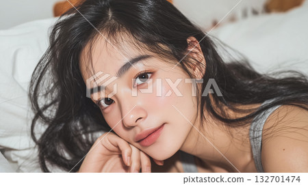 Korean woman relaxing in bed with natural makeup and long hair in a cozy room setting during the day Korean woman relaxing in bed with natural makeup and long hair in a cozy room setting during the day 132701474