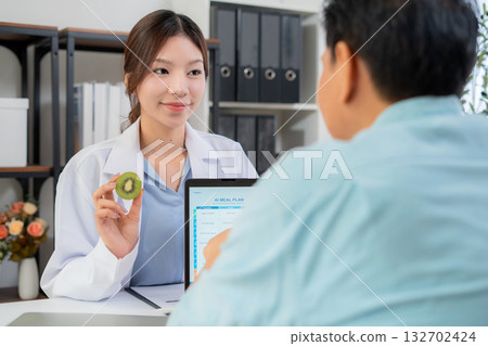 Asian nutritionist using tablet to explaining personalized meal plan with AI to patient. 132702424
