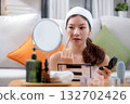 Beauty happy young asian woman applying makeup with brush looking mirror in living room. 132702426