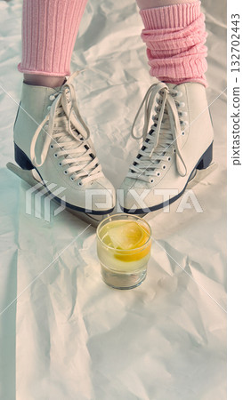 White ice skates and glass with lemon drink on crumpled white background White ice skates and glass with lemon drink on crumpled white background 132702443