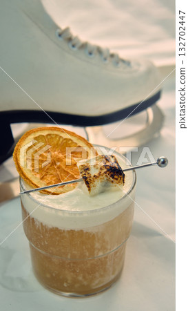 Close-up cocktail with dried orange and marshmallow beside ice skate Close-up cocktail with dried orange and marshmallow beside ice skate 132702447