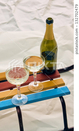 Bottle and two champagne glasses on colorful sledge in winter setting 132702479
