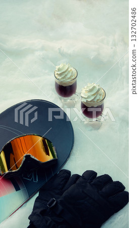 Snowboard goggles gloves and hot drinks with whipped cream on snow Snowboard goggles gloves and hot drinks with whipped cream on snow 132702486