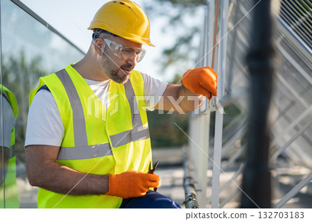 Technician working on rooftop installing and inspecting solar panels Technician working on rooftop installing and inspecting solar panels 132703183