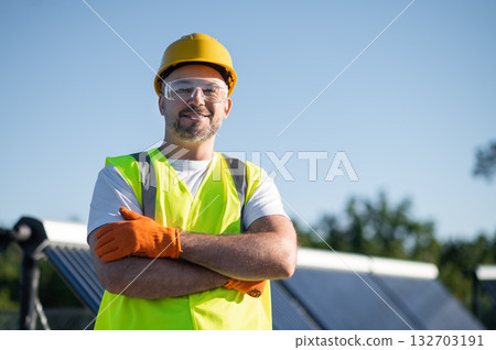 Worker standing beside solar installation smiling and Worker standing beside solar installation smiling and 132703191