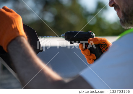 Man in hard hat repairing solar heating equipment outdoors in daylight Man in hard hat repairing solar heating equipment outdoors in daylight 132703196