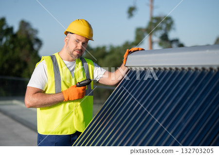 Worker checking and fixing photovoltaic installation on rooftop under sunlight 132703205