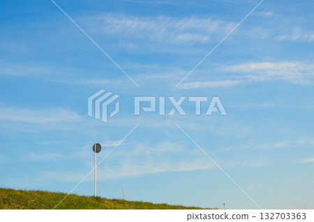 Blue sky with streaks of clouds and a road sign on a bank Blue sky with streaks of clouds and a road sign on a bank 132703363