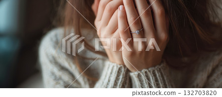 Woman shows engagement ring while sitting and expressing emotions in cozy environment 132703820