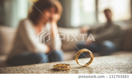 Woman removes her wedding ring during a moment of heartbreak in a cozy living room 132703883