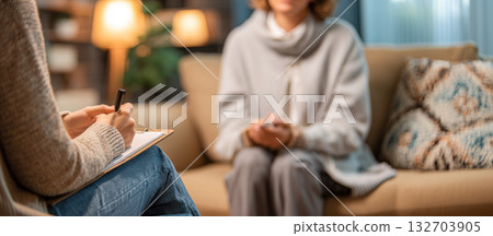 Psychologist conducts a counseling session with a patient in a cozy therapy room setting 132703905