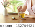 Woman hand stirring tea in a transparent cup 132704421