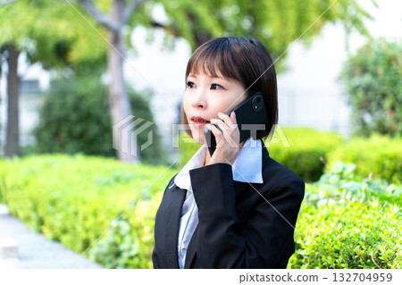 一個穿著西裝的女人在路上接聽電話 一個穿著西裝的女人在路上接聽電話 132704959