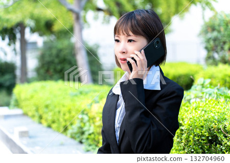 一個穿著西裝的女人在路上接聽電話 一個穿著西裝的女人在路上接聽電話 132704960