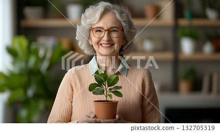 Cheerful Senior Woman Holding Potted Plant in Cozy Indoor Space with Greenery Cheerful Senior Woman Holding Potted Plant in Cozy Indoor Space with Greenery 132705319