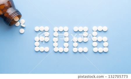 Happy New Year banner for medical theme. Number 2026 made by white pills spilling out of brown glass bottle on blue background. Creative idea for health care, medical and pharmacy concept. Happy New Year banner for medical theme. Number 2026 made by white pills spilling out of brown glass bottle on blue background. Creative idea for health care, medical and pharmacy concept. 132705773