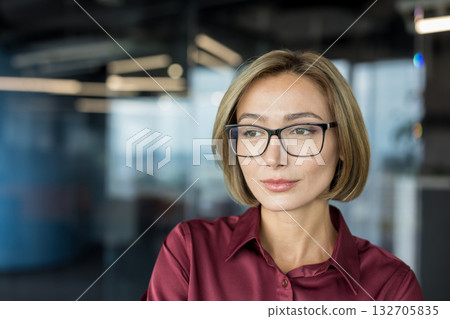 Professional businesswoman wearing glasses and a maroon shirt, confidently looking away in a modern office environment, representing leadership, vision, and sophisticated business success Professional businesswoman wearing glasses and a maroon shirt, confidently looking away in a modern office environment, representing leadership, vision, and sophisticated business success 132705835