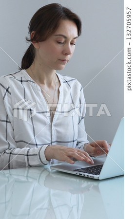 Professional businesswoman working on laptop, sitting at glass desk in bright contemporary workspace, embodying corporate success and concentration. Business people concept. Professional businesswoman working on laptop, sitting at glass desk in bright contemporary workspace, embodying corporate success and concentration. Business people concept. 132705957