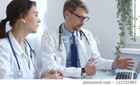 Two doctors are carefully studying medical charts on a laptop, discussing patient medical histories in a hospital or clinic. Medicine and healthcare concept. Two doctors are carefully studying medical charts on a laptop, discussing patient medical histories in a hospital or clinic. Medicine and healthcare concept. 132705963