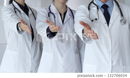 Medical team offering helping hands, extending invitation for support and showing professional care, welcoming patients to healthcare services with open palms 132706034
