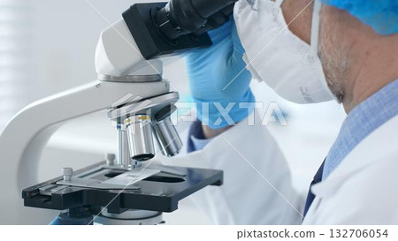 Microscope and scientist's hands in blue gloves adjusting close up in laboratory set. Medicine, science concept 132706054