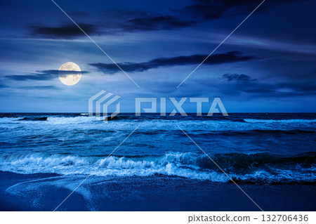 black sea waves crashing sandy beach at night. summer vacation on a windy weather under dark cloudy sky in full moon light. view of dramatic seascape. background for investment or abstract concepts 132706436