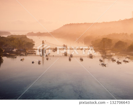 Aerial view of a bridge connecting two islands over ocean channel. Nusa Lembongan and Nusa Ceningan bridge with boats. Aerial view of a bridge connecting two islands over ocean channel. Nusa Lembongan and Nusa Ceningan bridge with boats. 132706643