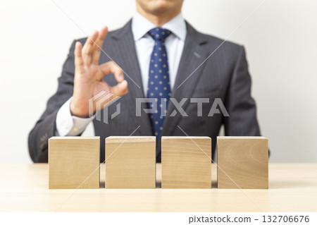 一位商人擺出「OK」的手勢，旁邊是一塊普通的積木。 132706676