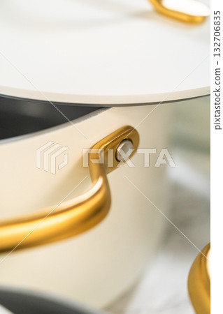 Macro view of a sleek golden pot lid and handle. Useful for branding materials, online shops, or elegant kitchen promotions. 132706835