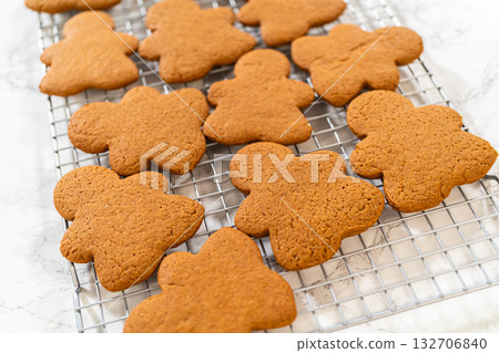 Freshly baked Orange Zest Gingerbread Cookies in gingerbread girl shapes cooling on a wire rack, viewed from an angled perspective. 132706840