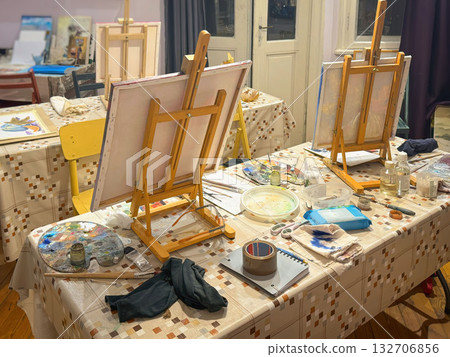 Art Studio with Easels and Painting Supplies. Indoor art studio with easels, canvases, paint palettes, tools arranged for painting session. Concept of painting, creative process, artistic workspace Art Studio with Easels and Painting Supplies. Indoor art studio with easels, canvases, paint palettes, tools arranged for painting session. Concept of painting, creative process, artistic workspace 132706856