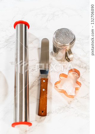 A flat lay of baking tools, including rolling pins and a gingerbread girl cookie cutter, set on a marble surface for preparing Orange Zest Gingerbread Cookies. A flat lay of baking tools, including rolling pins and a gingerbread girl cookie cutter, set on a marble surface for preparing Orange Zest Gingerbread Cookies. 132706890