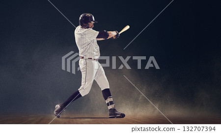 Baseball batter mid-swing making contact with ball on field under dramatic light Baseball batter mid-swing making contact with ball on field under dramatic light 132707394