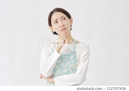 一位穿著圍裙的女子在白色背景下憂心忡忡 132707436