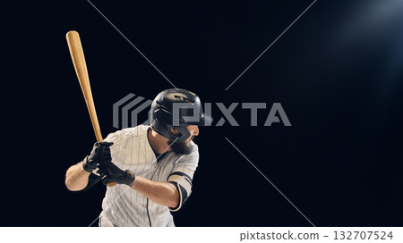 Baseball player holding bat ready to swing on dark studio background 132707524