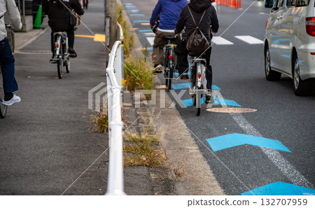 一輛自行車在道路上的自行車道上行駛，一輛汽車從旁邊駛過。 132707959