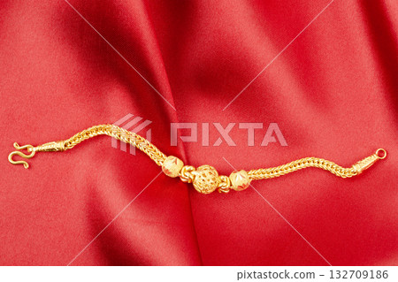 Gold chain necklace on red silk textile. 132709186