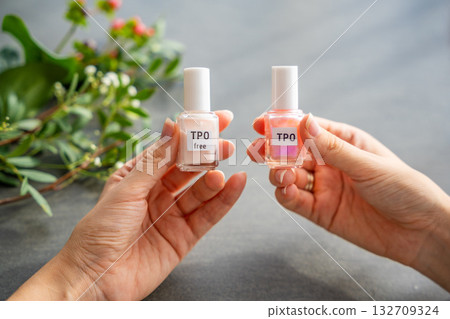 A woman compares two gel nail polish bottles labeled TPO and TPO free. The concept highlights awareness of harmful ingredients like Trimethylbenzoyl Diphenylphosphine Oxide. A woman compares two gel nail polish bottles labeled TPO and TPO free. The concept highlights awareness of harmful ingredients like Trimethylbenzoyl Diphenylphosphine Oxide. 132709324