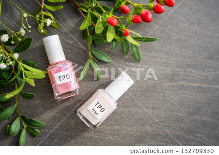 Two gel nail polish bottles labeled TPO and TPO Free on a table with flowers. Concept of chemical awareness and safe beauty products without Trimethylbenzoyl Diphenylphosphine Oxide 132709330