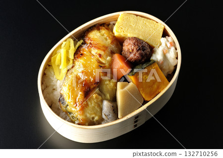 Grilled fish bento photographed against a black background Grilled fish bento photographed against a black background 132710256