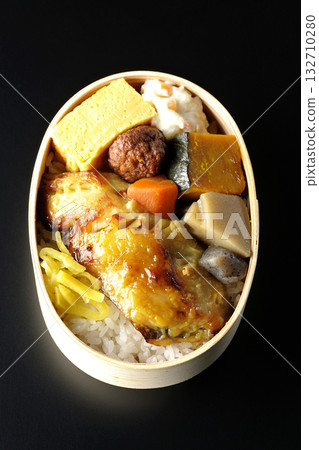 Grilled fish bento photographed against a black background Grilled fish bento photographed against a black background 132710280