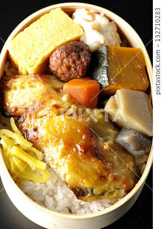 Grilled fish bento photographed against a black background Grilled fish bento photographed against a black background 132710283