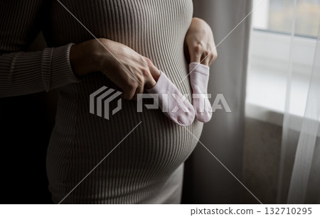 Pregnant woman showing cute pink baby socks Pregnant woman showing cute pink baby socks 132710295