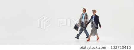Two professionals walking together with briefcases expressing cooperation and forward momentum. Banner 132710410