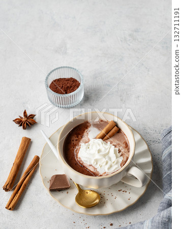 Hot chocolate in a cup with whipped cream and spices on a light background with napkin. 132711191