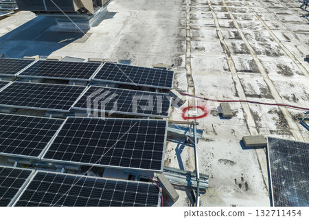 Broken down photovoltaic solar panels destroyed by hurricane Ian winds mounted on industrial building roof for producing green ecological electricity. Consequences of natural disaster 132711454